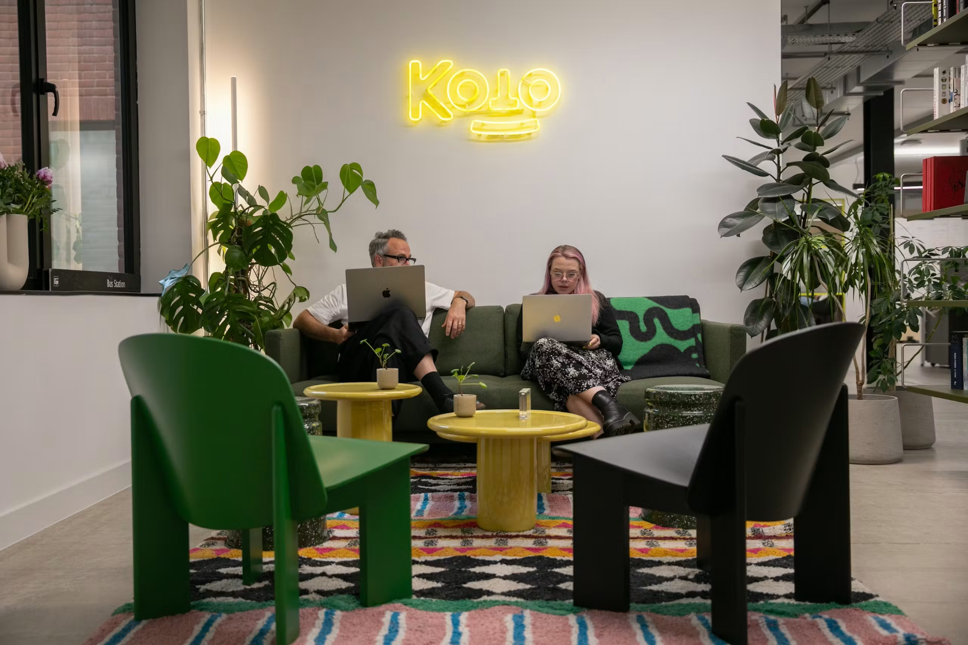 Koto studio interior with team members working under a neon Koto sign