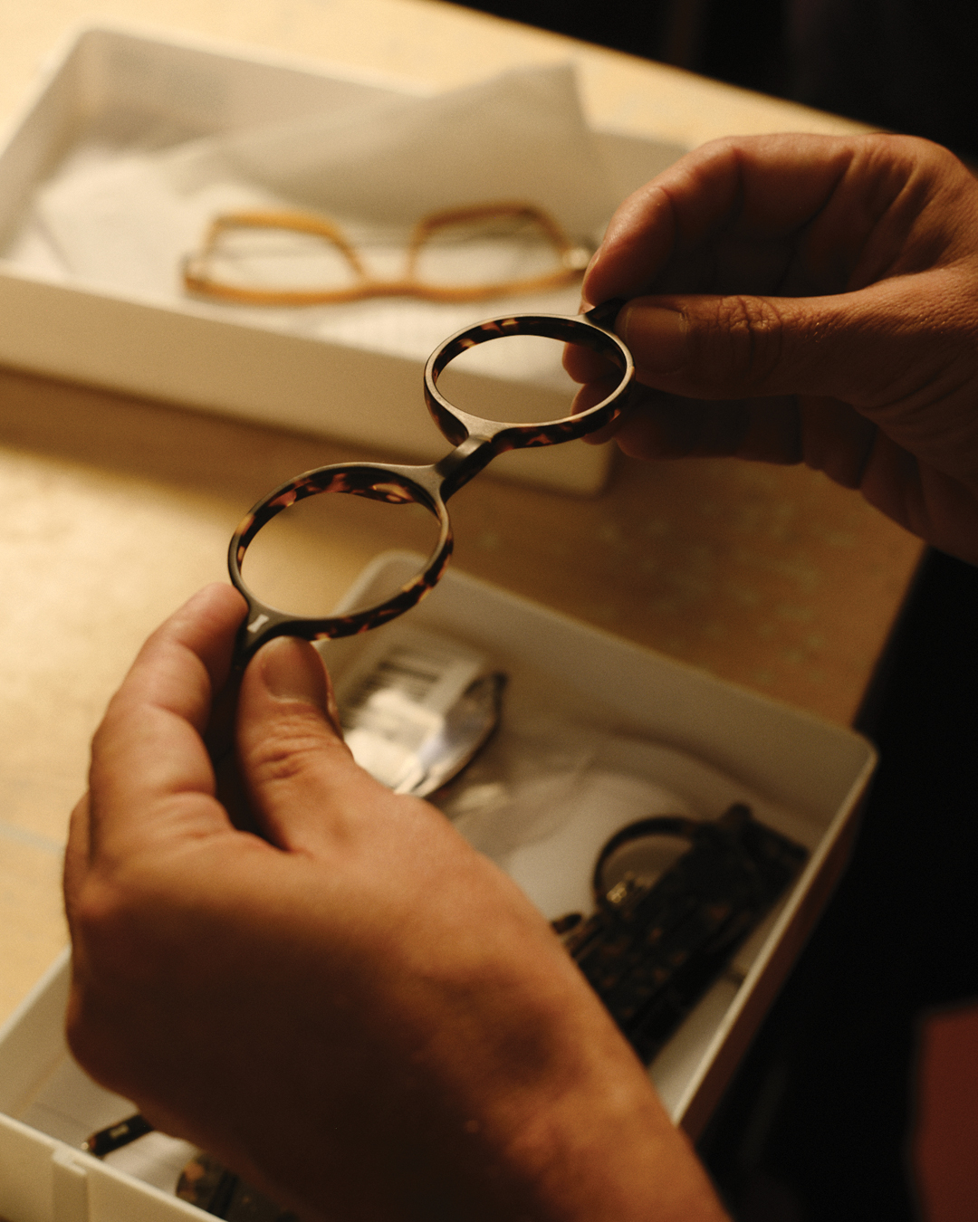 Hands holding a tortoiseshell Cubitts frame over a workshop tray