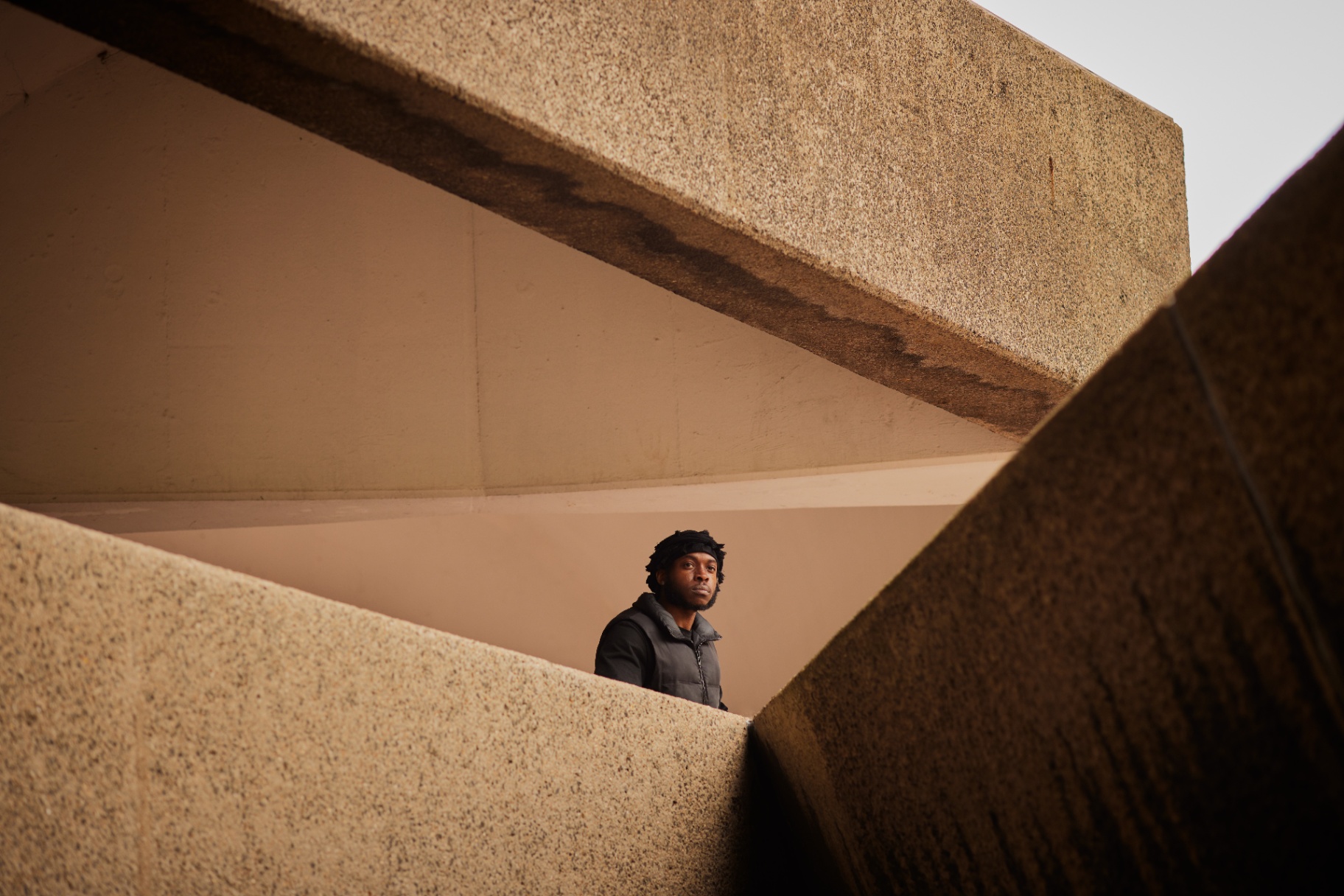 A young man framed by concrete brutalist architecture