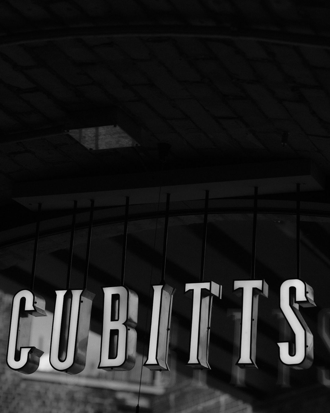Cubitts illuminated shop sign in black and white
