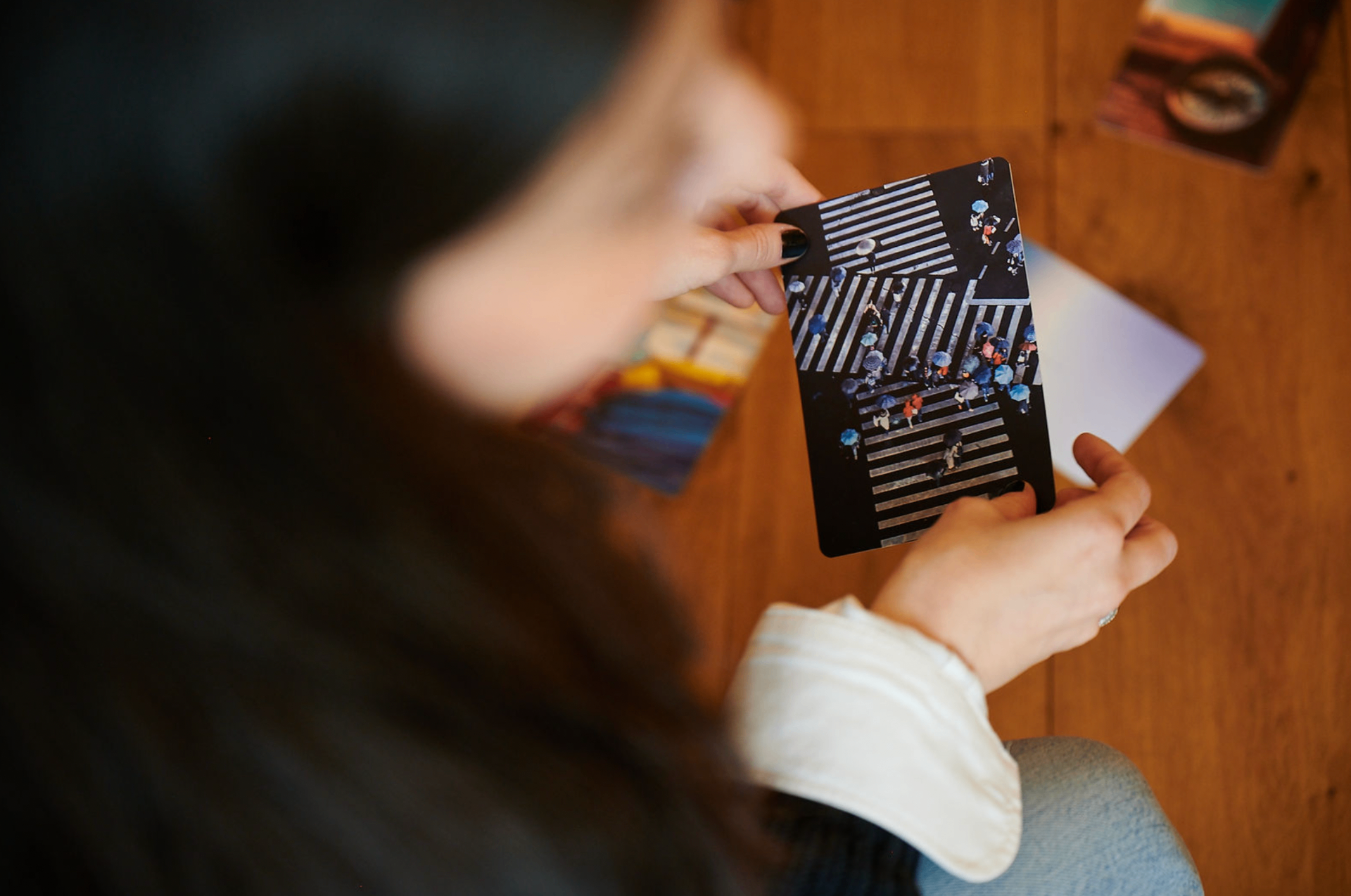 A hand holding a black YCN card featuring an aerial photograph of umbrellas on a striped crossing
