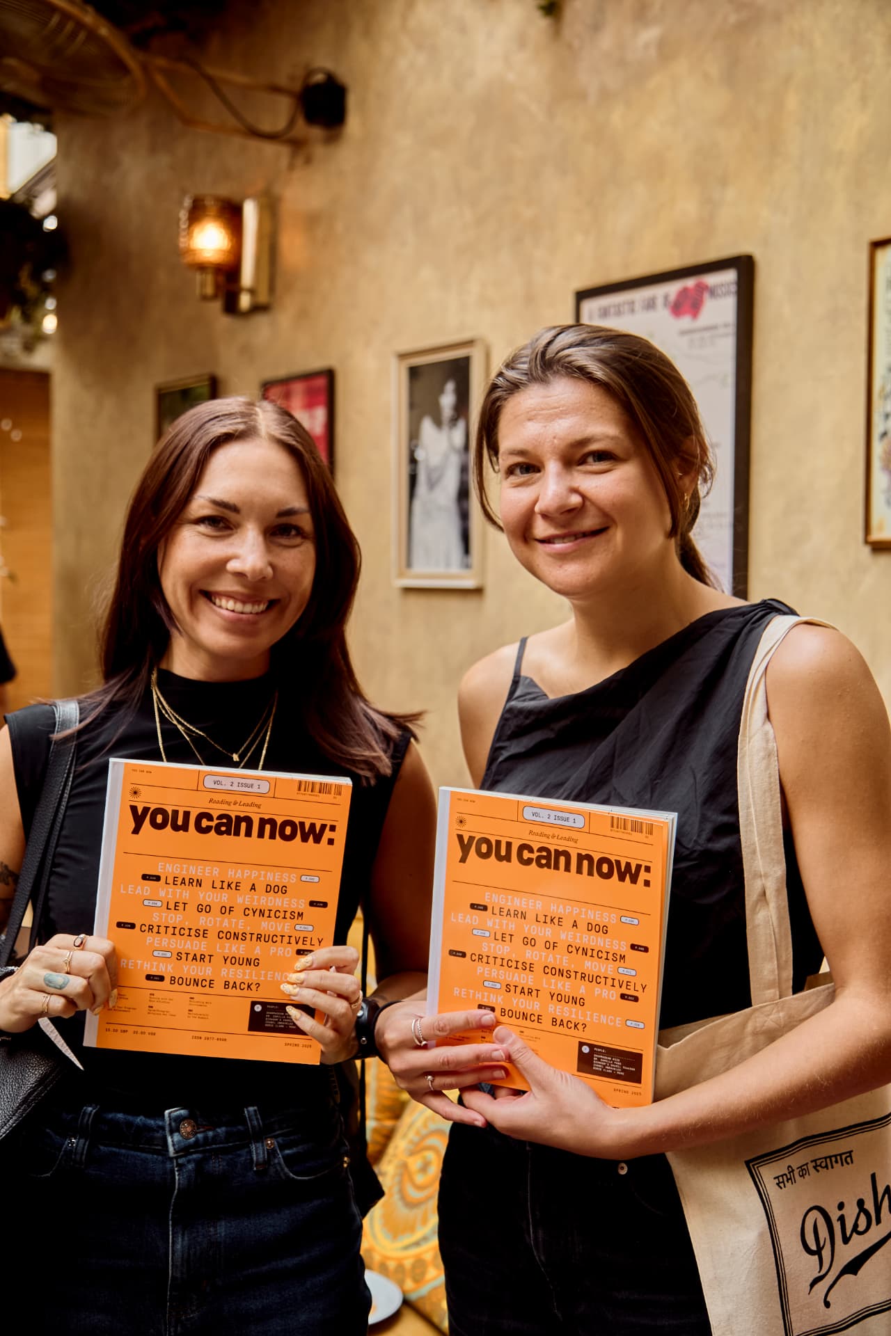 Two guests smiling and holding up the latest issue of You Can Now