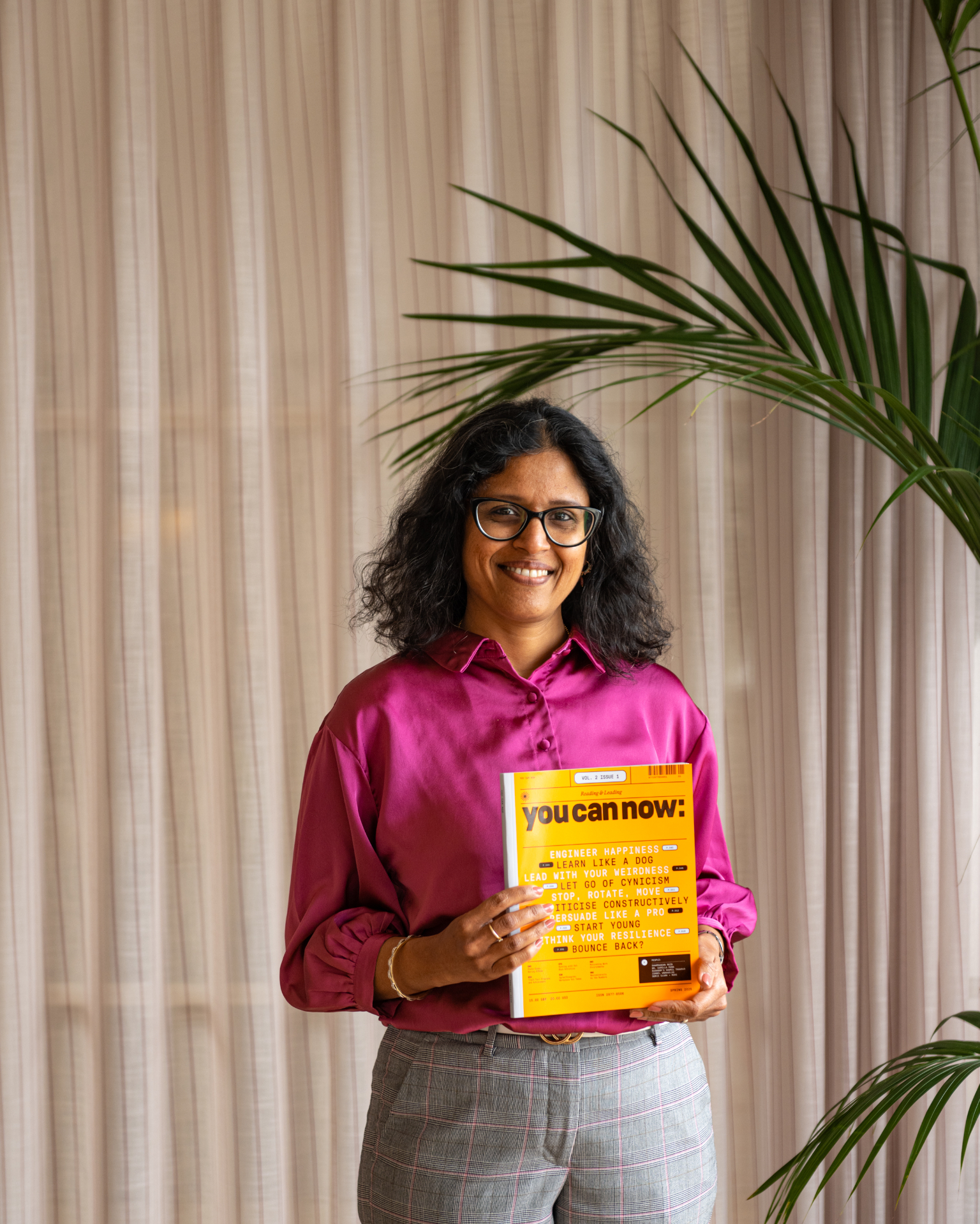 A leader smiling and holding a You Can Now magazine